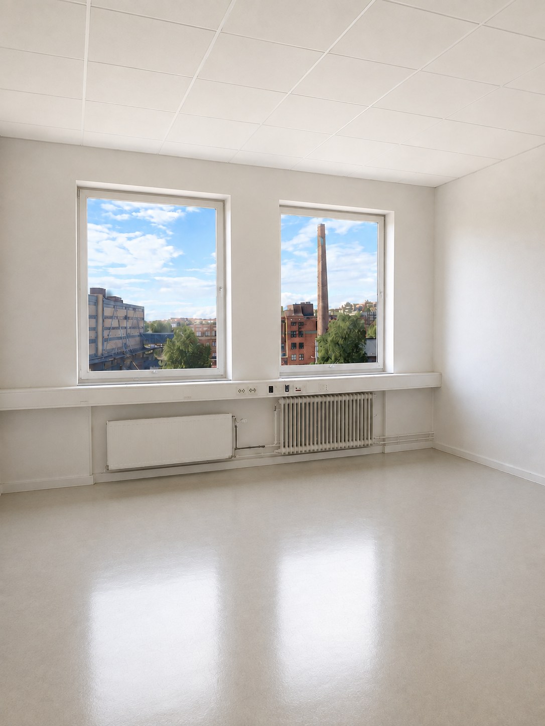 An empty studio at Färgkontoret, with two windows looking out over the Lövholmen chimney