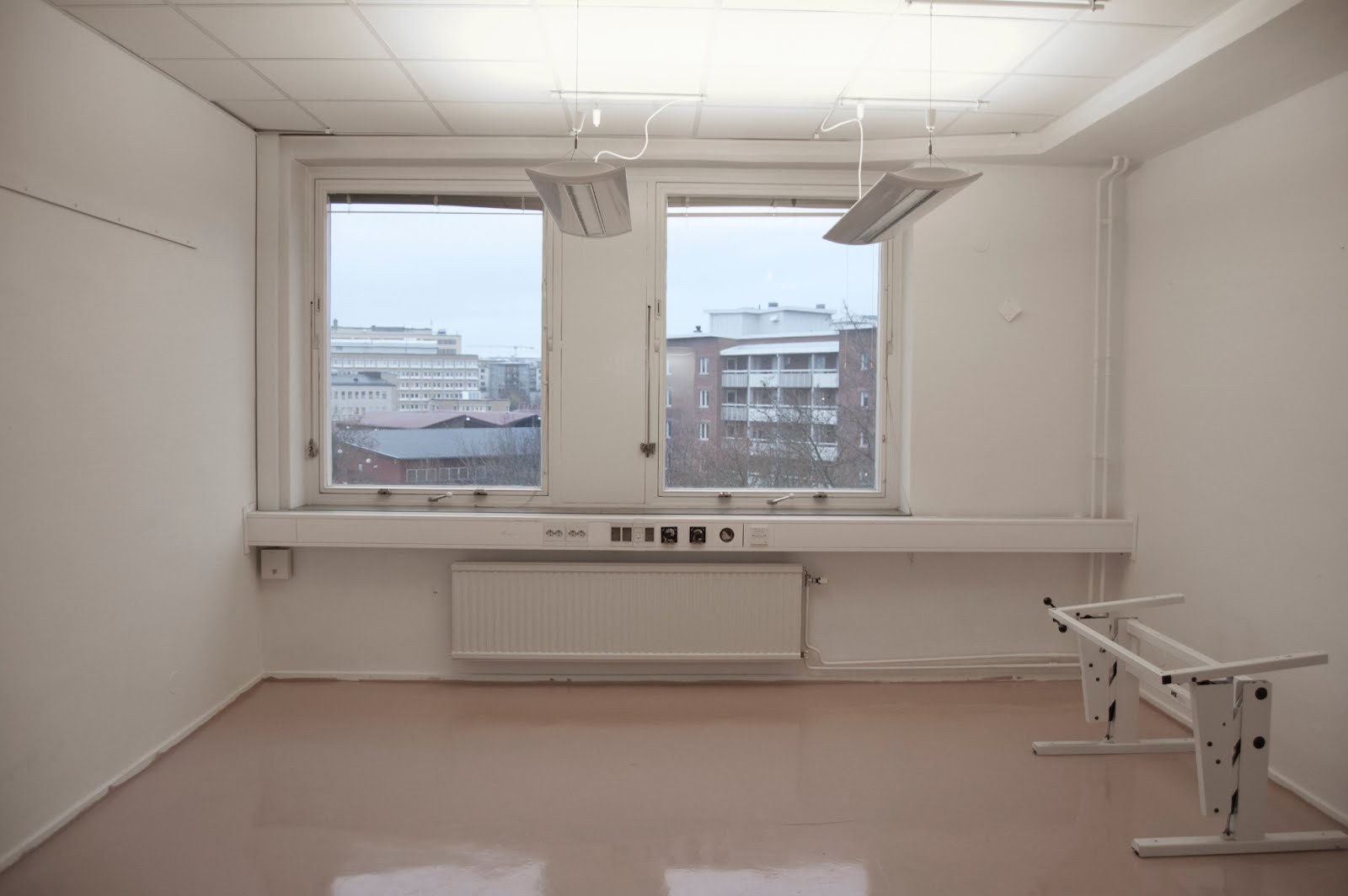 An empty studio at Färgkontoret with a pale floor and a wide window over the rooftops